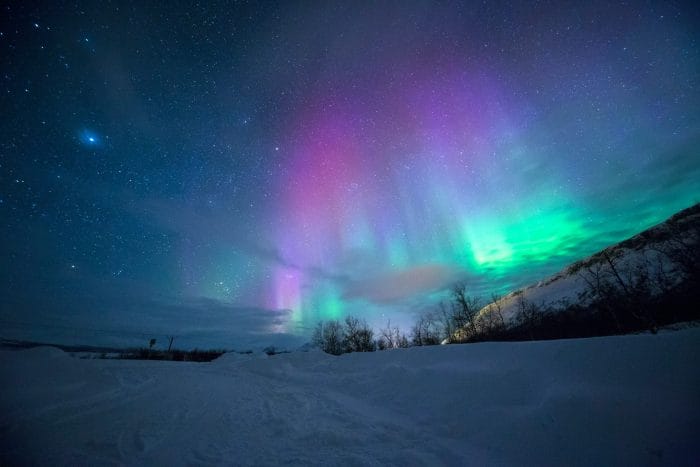 Imagen de una aurora boreal con tonos violetas y azulados